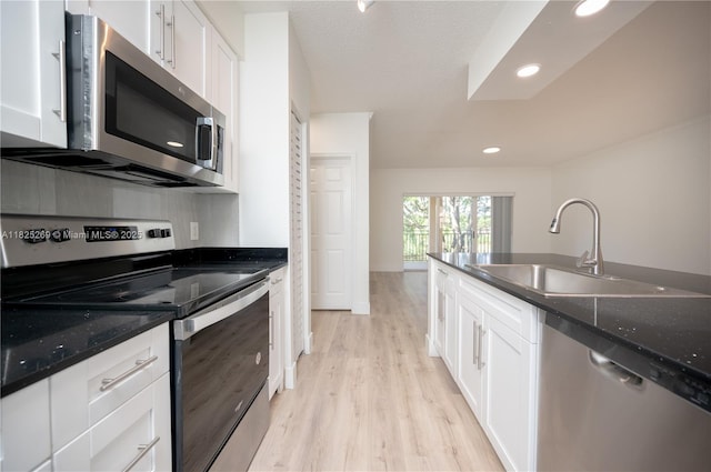 2406 Centergate Dr Unit 202, Miramar, FL 33025 - kitchen featuring appliances with stainless steel finishes, white cabinets, light wood-style flooring, recessed lighting, and dark stone countertops