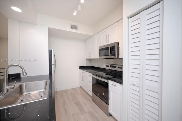 2406 Centergate Dr Unit 202, Miramar, FL 33025 - kitchen with appliances with stainless steel finishes, white cabinetry, backsplash, light wood finished floors, and dark countertops