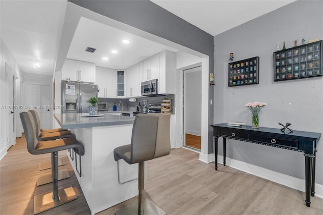 3610 NW 171st St, Miami Gardens, FL 33056 - kitchen featuring stainless steel appliances, light wood-style flooring, a breakfast bar area, white cabinetry, and glass insert cabinets