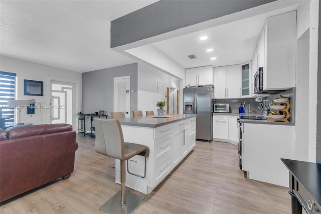3610 NW 171st St, Miami Gardens, FL 33056 - kitchen featuring stainless steel appliances, light wood-style flooring, white cabinets, decorative backsplash, and a kitchen island
