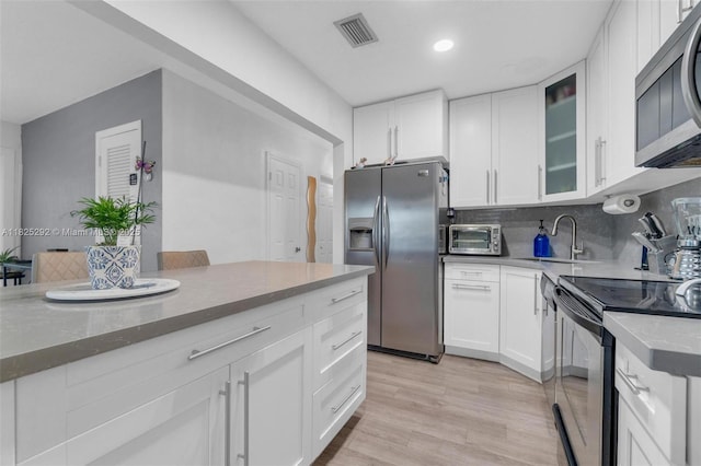 3610 NW 171st St, Miami Gardens, FL 33056 - kitchen featuring stainless steel appliances, white cabinets, glass insert cabinets, light wood-style floors, and recessed lighting