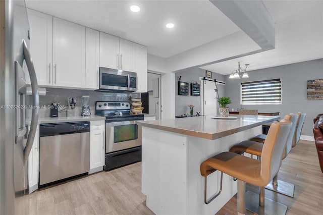 3610 NW 171st St, Miami Gardens, FL 33056 - kitchen featuring stainless steel appliances, white cabinetry, a breakfast bar area, light wood-style floors, and light countertops