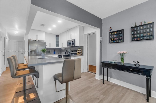 3610 NW 171st St, Miami Gardens, FL 33056 - kitchen featuring appliances with stainless steel finishes, light wood-type flooring, a kitchen breakfast bar, glass insert cabinets, and recessed lighting