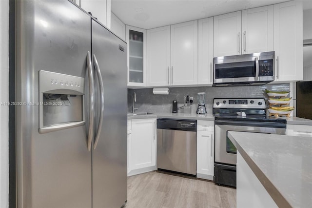 3610 NW 171st St, Miami Gardens, FL 33056 - kitchen featuring stainless steel appliances, white cabinetry, decorative backsplash, glass insert cabinets, and light wood-type flooring