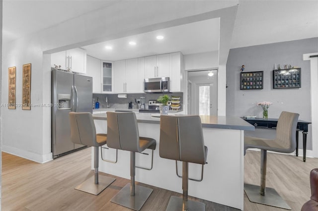 3610 NW 171st St, Miami Gardens, FL 33056 - kitchen featuring appliances with stainless steel finishes, light wood-type flooring, a breakfast bar, glass insert cabinets, and white cabinetry