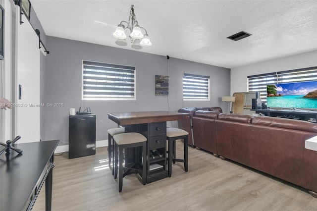 3610 NW 171st St, Miami Gardens, FL 33056 - dining room with a barn door, light wood-type flooring, a chandelier, and a textured ceiling
