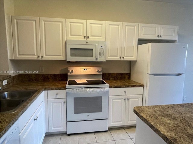 3550 Oleander Ter, Riviera Beach, FL 33404 - kitchen with white appliances, light tile patterned floors, and dark countertops