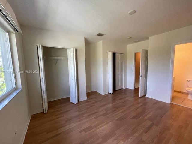3550 Oleander Ter, Riviera Beach, FL 33404 - unfurnished bedroom with two closets, wood finished floors, a textured ceiling, and ensuite bath