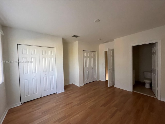 3550 Oleander Ter, Riviera Beach, FL 33404 - unfurnished bedroom with multiple closets, wood finished floors, and ensuite bath