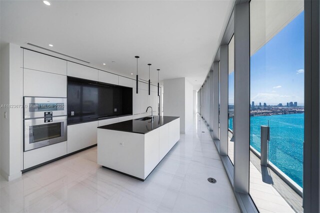 300 Biscayne Blvd Way Unit 4301, Miami, FL 33131 - kitchen with modern cabinets, white cabinetry, dark countertops, an island with sink, and hanging light fixtures