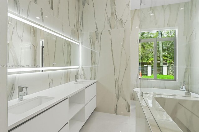 7025 SW 80th Ct, Miami, FL 33143 - bathroom with double vanity, a tub with marble appearance, plenty of natural light, tile patterned floors, and tile walls