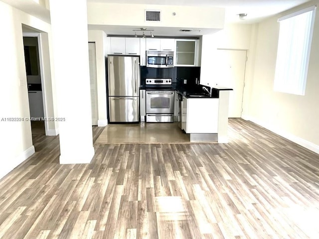 3339 Virginia St Unit 205, Miami, FL 33133 - kitchen featuring stainless steel appliances, dark countertops, white cabinetry, and wood finished floors