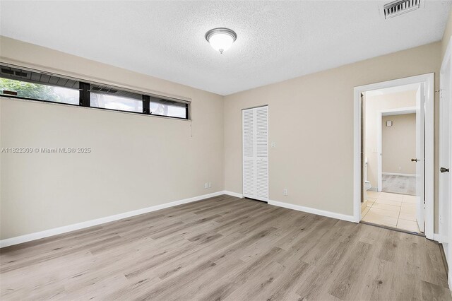 608 Saint Andrews Rd Unit 46, Hollywood, FL 33021 - unfurnished bedroom with multiple windows, light wood-style flooring, a closet, and a textured ceiling