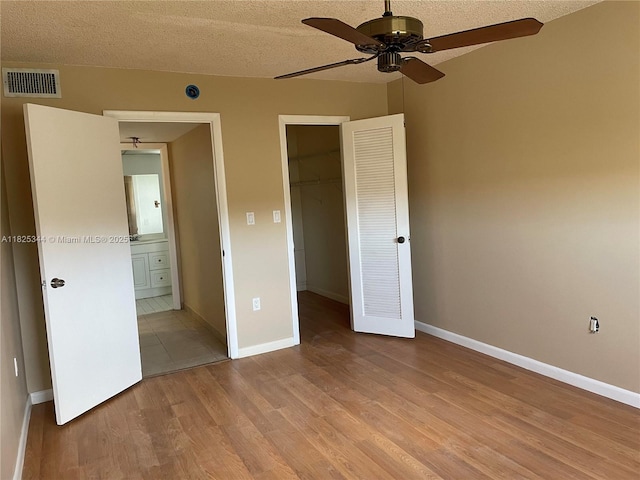 8325 Sunrise Lakes Blvd Unit 305, Sunrise, FL 33322 - unfurnished bedroom featuring light wood-style flooring, a spacious closet, a textured ceiling, a closet, and ensuite bath
