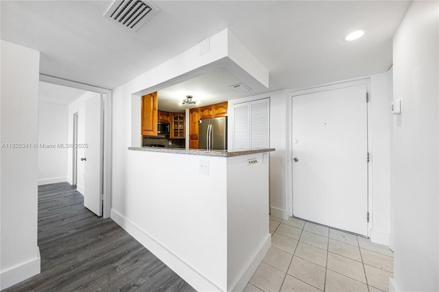 10700 SW 108th Ave Unit C316, Miami, FL 33176 - kitchen featuring freestanding refrigerator, brown cabinetry, a peninsula, and light tile patterned floors
