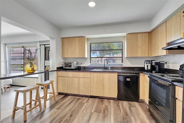 4764 Greentree Cres Unit A, Boynton Beach, FL 33436 - kitchen with black appliances, light brown cabinetry, light wood-type flooring, under cabinet range hood, and dark stone countertops