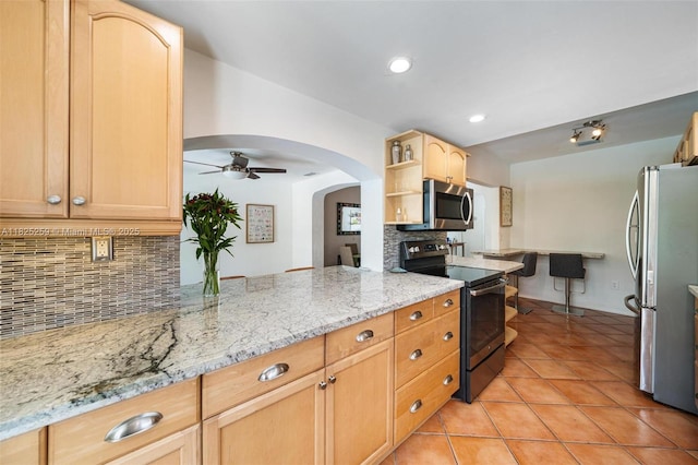 443 SW 18th Rd, Miami, FL 33129 - kitchen featuring appliances with stainless steel finishes, ceiling fan, backsplash, arched walkways, and light tile patterned floors