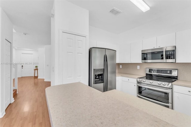 8081 NW 107th Ct, Doral, FL 33178 - kitchen with appliances with stainless steel finishes, light wood-style floors, white cabinetry, and light countertops