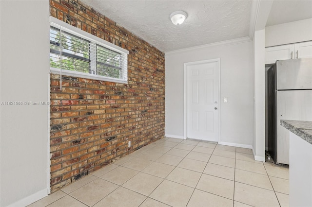 2817 SW 8th St, Fort Lauderdale, FL 33312 - kitchen featuring freestanding refrigerator, brick wall, white cabinetry, a textured ceiling, and light tile patterned floors