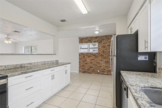 2817 SW 8th St, Fort Lauderdale, FL 33312 - kitchen featuring brick wall, a textured ceiling, white cabinetry, light tile patterned floors, and light stone counters