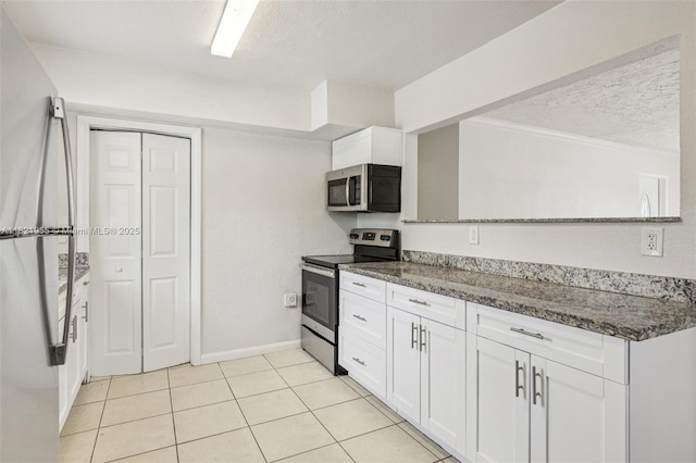 2817 SW 8th St, Fort Lauderdale, FL 33312 - kitchen with stainless steel appliances, white cabinets, a textured ceiling, dark stone counters, and light tile patterned flooring