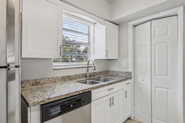 2817 SW 8th St, Fort Lauderdale, FL 33312 - kitchen with stainless steel dishwasher, white cabinets, light stone countertops, and freestanding refrigerator