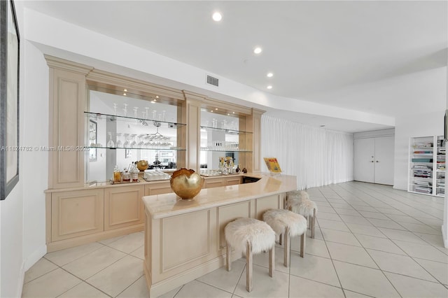 9601 Collins Ave Unit 809, Bal Harbour, FL 33154 - kitchen with cream cabinetry, light tile patterned floors, light countertops, a breakfast bar, and open floor plan