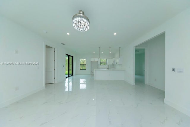 719 Almelia St E, Lehigh Acres, FL 33974 - unfurnished living room with a chandelier, recessed lighting, and light marble finish floors