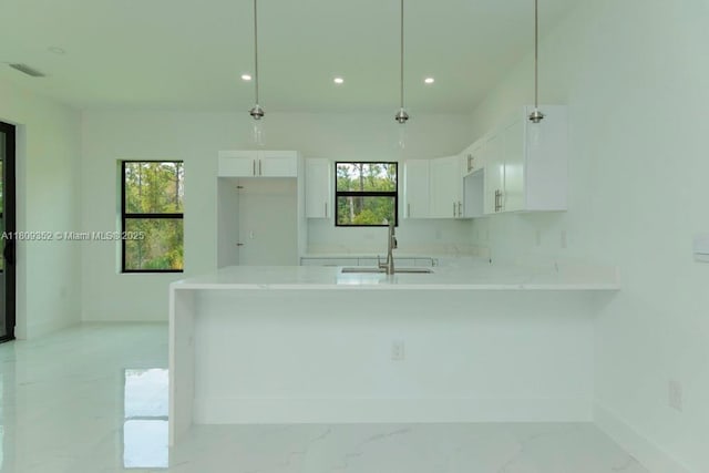 719 Almelia St E, Lehigh Acres, FL 33974 - kitchen with a peninsula, white cabinets, light countertops, light marble finish flooring, and recessed lighting