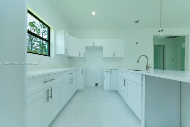 719 Almelia St E, Lehigh Acres, FL 33974 - kitchen featuring white cabinets, light marble finish floors, pendant lighting, a peninsula, and light stone countertops