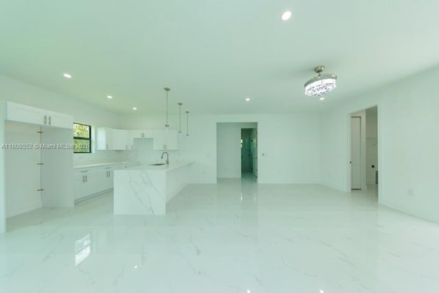 719 Almelia St E, Lehigh Acres, FL 33974 - kitchen featuring recessed lighting, white cabinetry, open floor plan, light marble finish floors, and light countertops