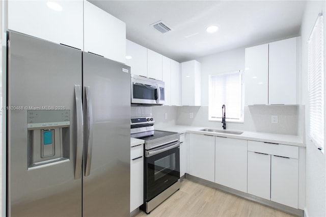 2250 NW 95th Ter, Miami, FL 33147 - kitchen featuring stainless steel appliances, white cabinetry, light countertops, and light wood-type flooring
