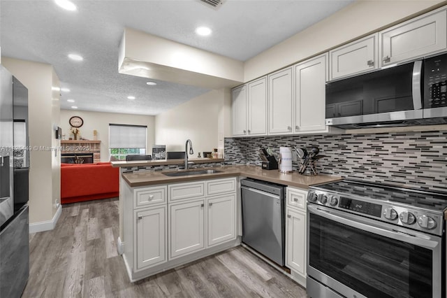 11664 NW 19th Dr, Coral Springs, FL 33071 - kitchen with appliances with stainless steel finishes, a peninsula, open floor plan, light wood-style flooring, and backsplash