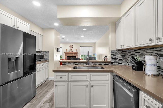 11664 NW 19th Dr, Coral Springs, FL 33071 - kitchen with stainless steel appliances, a peninsula, white cabinets, tasteful backsplash, and light wood-style flooring