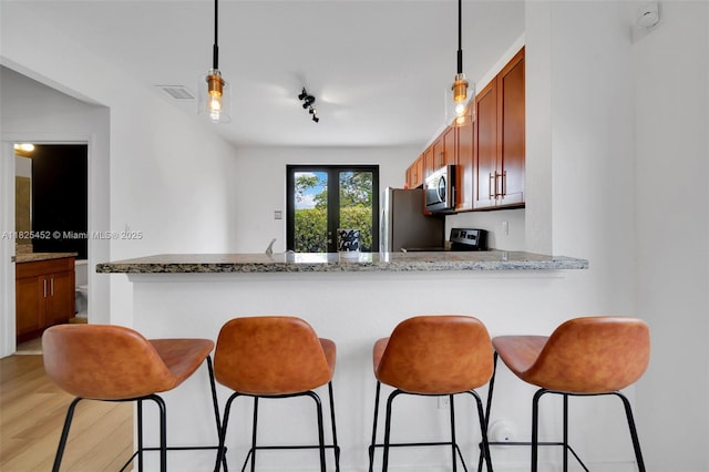 23061 SW 114th Path, Miami, FL 33170 - kitchen featuring appliances with stainless steel finishes, brown cabinets, hanging light fixtures, and a breakfast bar