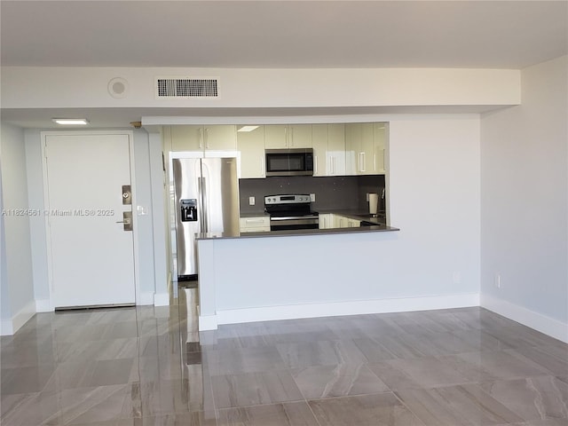 13499 Biscayne Blvd Unit 1105, North Miami, FL 33181 - kitchen featuring appliances with stainless steel finishes, dark countertops, cream cabinets, and a peninsula