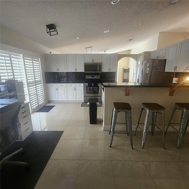 2017 NW 182nd Ave, Pembroke Pines, FL 33029 - kitchen with stainless steel appliances, a textured ceiling, a peninsula, tasteful backsplash, and a breakfast bar