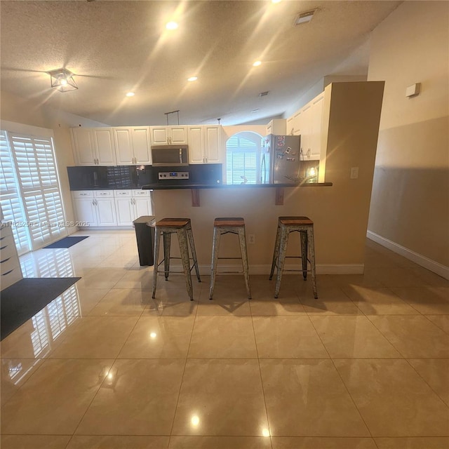 2017 NW 182nd Ave, Pembroke Pines, FL 33029 - kitchen with appliances with stainless steel finishes, a peninsula, a breakfast bar area, white cabinets, and lofted ceiling