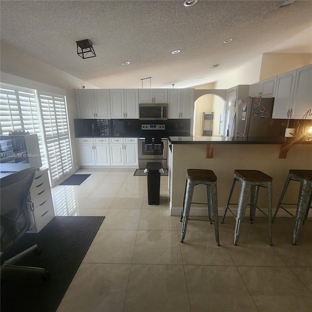 2017 NW 182nd Ave, Pembroke Pines, FL 33029 - kitchen with stainless steel appliances, a textured ceiling, a peninsula, tasteful backsplash, and a breakfast bar