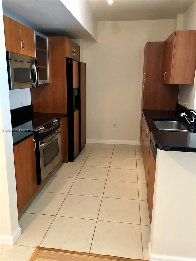 18800 NE 29th Ave Unit 730, Aventura, FL 33180 - kitchen with stainless steel appliances, dark countertops, brown cabinets, and light tile patterned floors