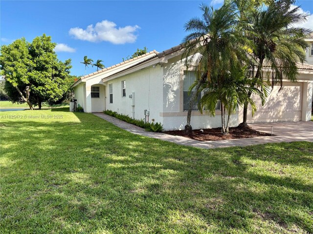 2091 SW 157th Ave, Miramar, FL 33027 - view of home's exterior featuring a garage, stucco siding, a yard, a tile roof, and driveway