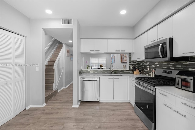 11000 Sand Piper Ct, Tamarac, FL 33321 - kitchen with appliances with stainless steel finishes, light countertops, white cabinetry, tasteful backsplash, and light wood-style flooring