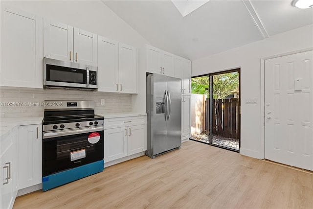7720 NW 79th Ave Unit B6, Tamarac, FL 33321 - kitchen with appliances with stainless steel finishes, backsplash, light wood finished floors, white cabinetry, and vaulted ceiling