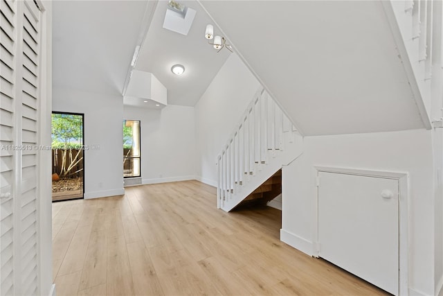 7720 NW 79th Ave Unit B6, Tamarac, FL 33321 - unfurnished living room with stairway, a skylight, light wood-style floors, and vaulted ceiling