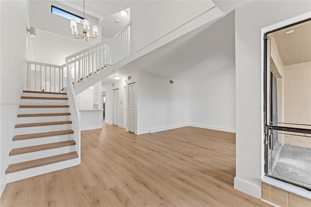 7720 NW 79th Ave Unit B6, Tamarac, FL 33321 - unfurnished living room featuring a chandelier, wood finished floors, stairs, and a towering ceiling