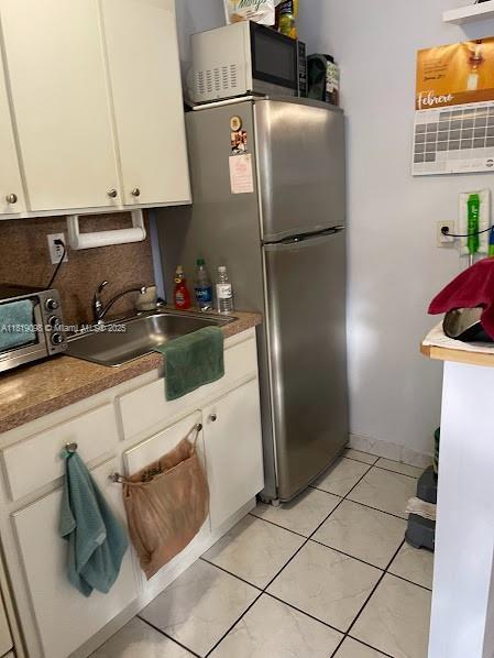 829 SW 19th Ave, Miami, FL 33135 - kitchen with white cabinetry, decorative backsplash, and light tile patterned floors