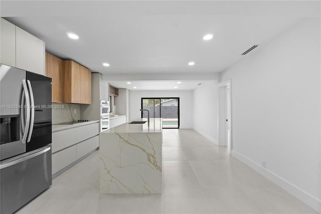 2231 N 49th Ave, Hollywood, FL 33021 - kitchen with appliances with stainless steel finishes, modern cabinets, light stone counters, recessed lighting, and a center island with sink