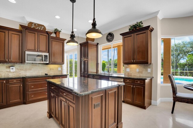 11844 Foxbriar Lake Trl, Boynton Beach, FL 33473 - kitchen featuring stainless steel microwave, decorative backsplash, hanging light fixtures, dark stone counters, and a center island