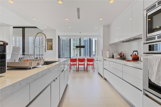 520 Brickell Key Dr Unit A1421, Miami, FL 33131 - kitchen featuring appliances with stainless steel finishes, modern cabinets, white cabinetry, recessed lighting, and light stone countertops