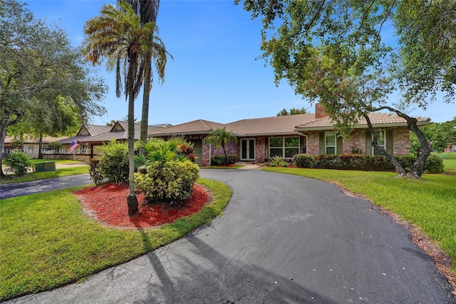 10967 NW 12th Dr, Coral Springs, FL 33071 - ranch-style home featuring curved driveway, a tiled roof, a front yard, a chimney, and stone siding